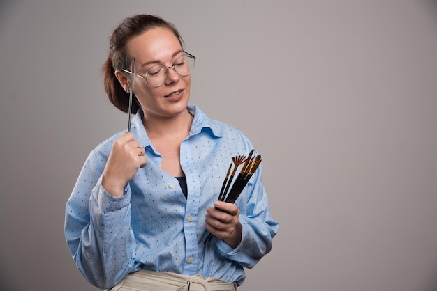 L'artiste femme détient des pinceaux sur gris. photo de haute qualité