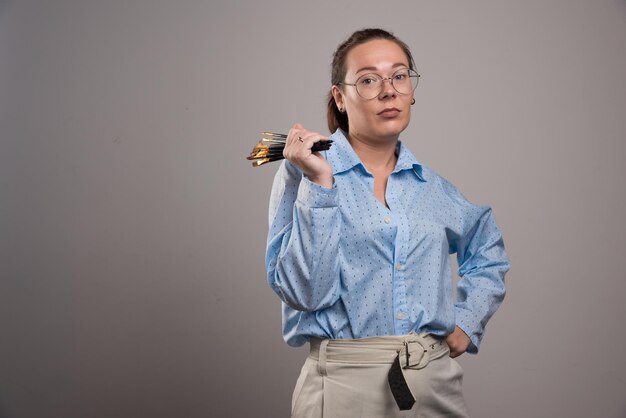 L'artiste femme détient des pinceaux sur gris. photo de haute qualité