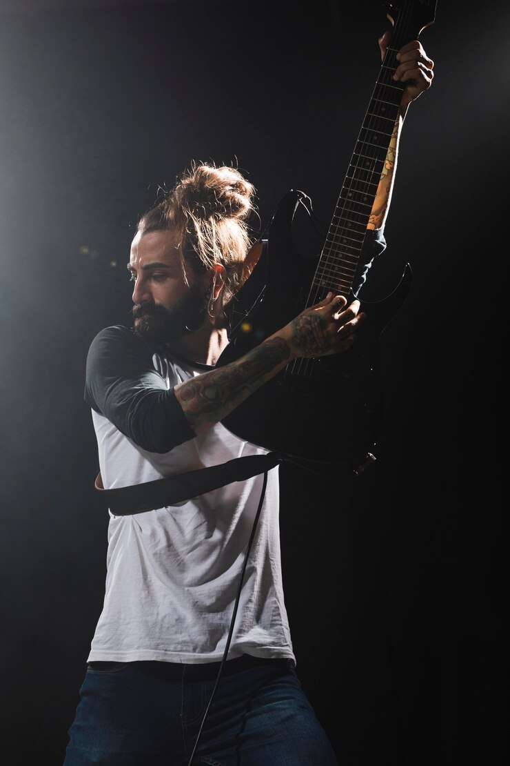 Photo gratuit artiste jouant de la guitare et tenant l'instrument en l'air