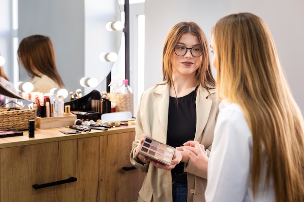 Artiste maquilleur montrant la palette à la femme