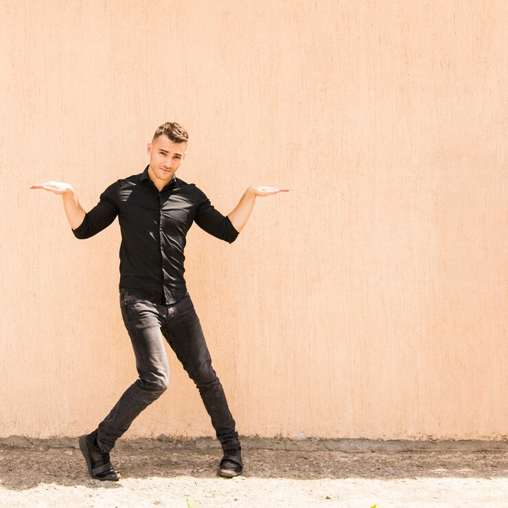 Photo gratuit artiste de rue posant contre le mur beige