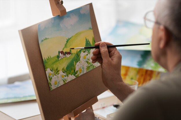 Photo gratuite artiste senior dans le studio peignant à l'aquarelle