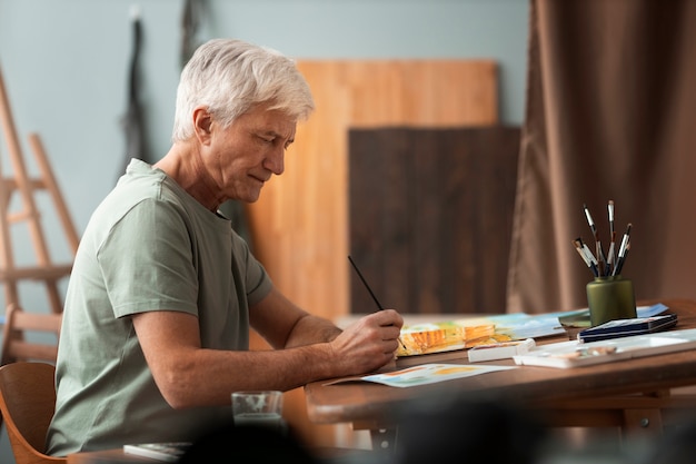 Photo gratuite artiste senior dans le studio peignant à l'aquarelle