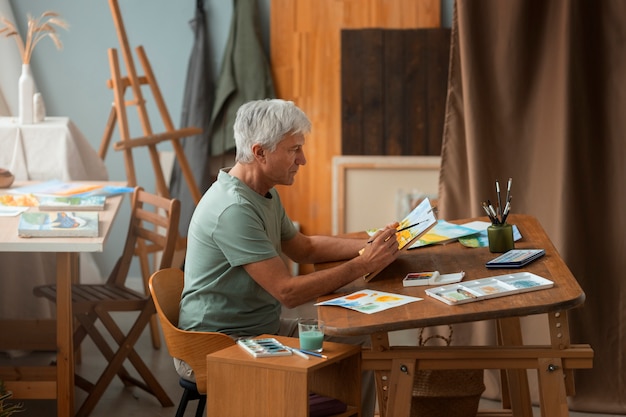 Artiste senior dans le studio peignant à l'aquarelle