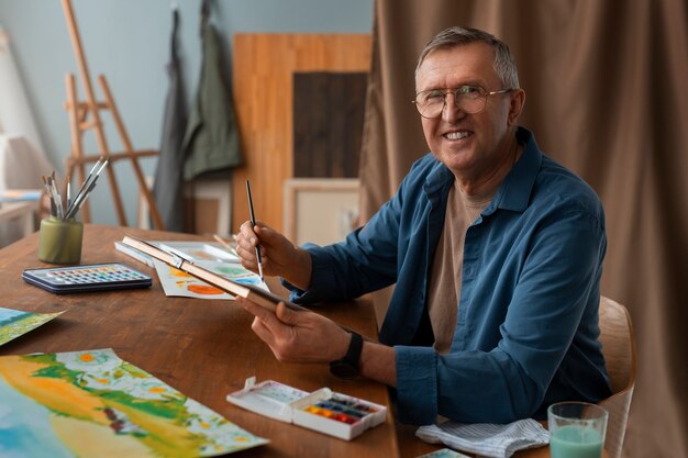 Artiste senior dans le studio peignant à l'aquarelle