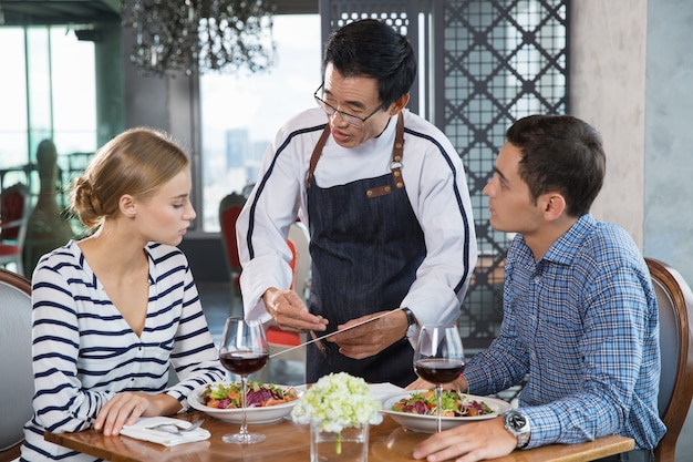 Photo gratuite asian waiter faire recommandation à jeune couple