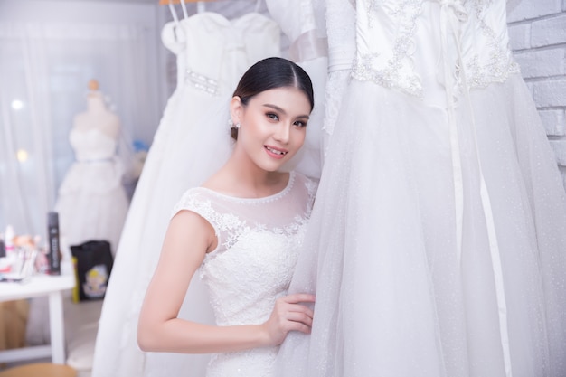 Asiatique jeune femme mariée essayant de robe de mariée au mariage moderne