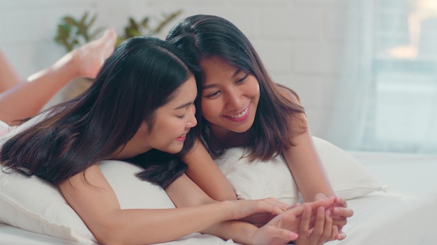 Asiatiques lesbiennes lgbtq couple de femmes s'embrassent et se font câlin sur le lit à la maison.