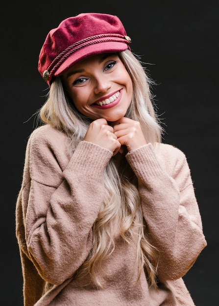 Photo gratuite assez souriante jeune femme debout près de fond noir en regardant la caméra