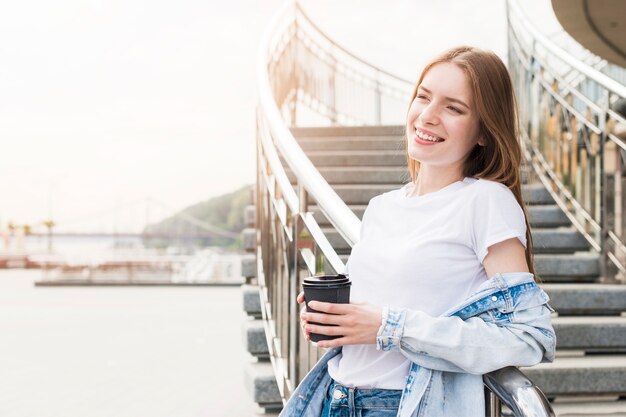 Assez souriante jeune femme se penchant sur la rambarde métallique