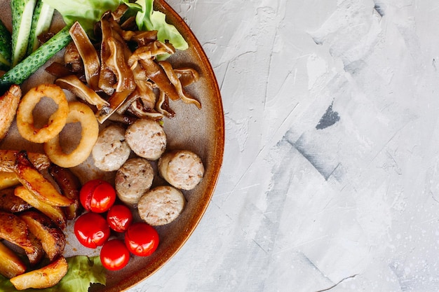 Assiette d'argile pleine d'apéritifs servis avec des pépites de poulet dorées cuites avec une croûte croustillante de délicieux canapés avec du hareng et des tomates cerises sauce à l'ail décorées de salade fraîche et de fromage