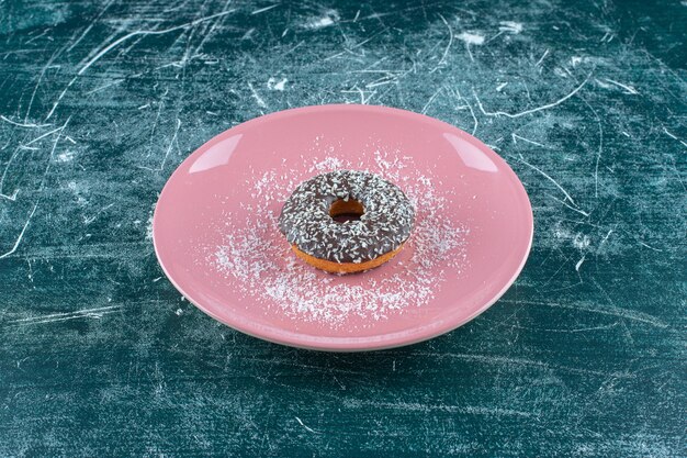 Une assiette de beignet au chocolat, sur la table bleue.