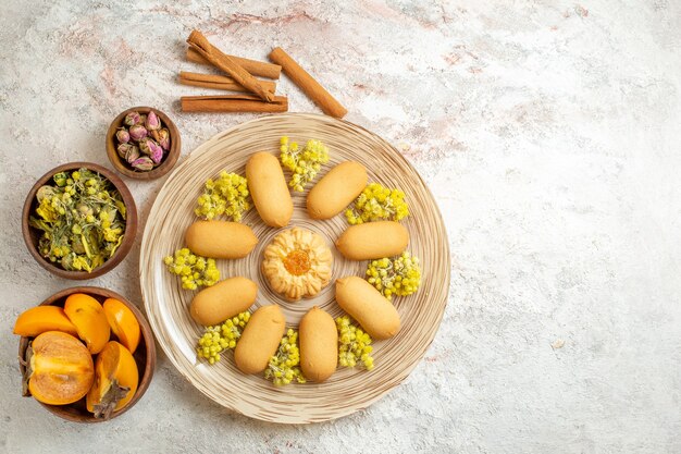 Une assiette de biscuits et de bâtons de cannelle et de fleurs séchées et de palmiers sur le côté gauche du sol