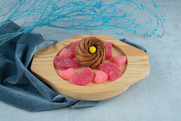 Assiette de biscuits et marmelades sur une serviette à côté de branches décoratives sur marbre.