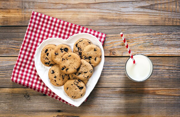 Photo gratuite assiette avec des biscuits et un verre de lait sur un fond plat en bois