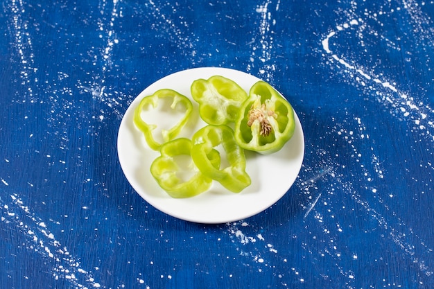 Assiette blanche d'anneaux de poivron vert sur une surface en marbre