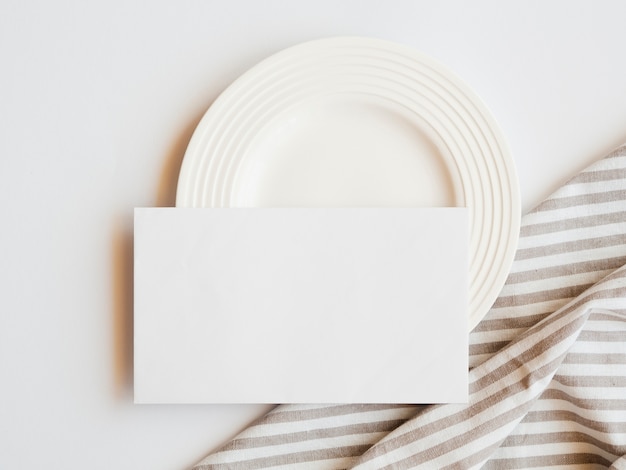 Assiette blanche avec un blanc vide et une nappe rayée marron et blanche sur fond blanc