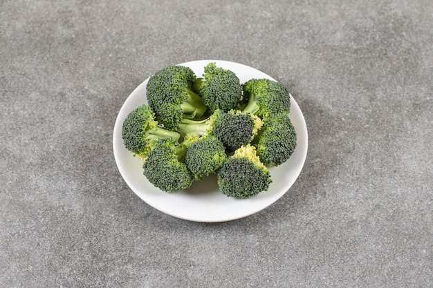 Assiette blanche de brocoli frais en bonne santé sur table en pierre.