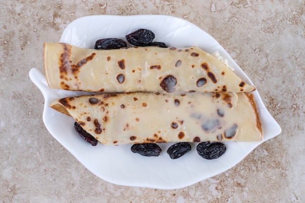 Une assiette blanche avec des crêpes et des baies