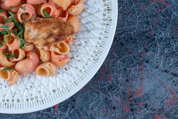 Une assiette blanche de délicieux macaronis et viande de poulet