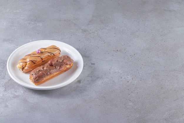 Assiette Blanche Avec éclairs Au Caramel Et Au Chocolat Sur La Surface De La Pierre