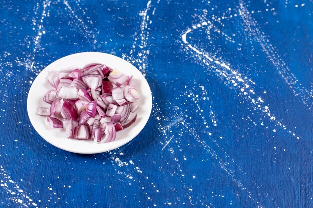 Assiette blanche d'oignons violets tranchés sur une surface en marbre