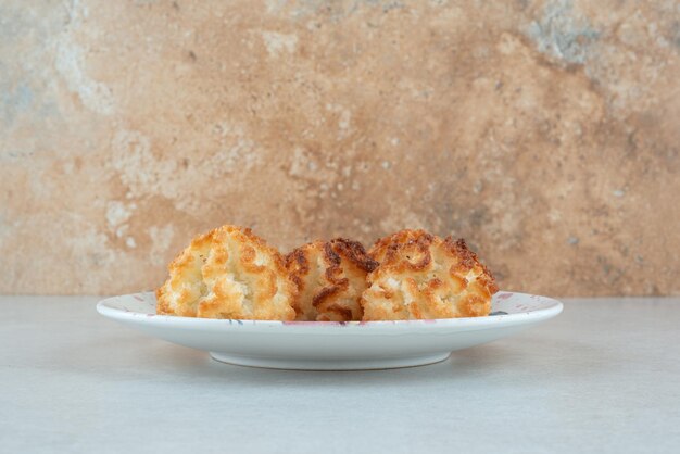 Une assiette blanche pleine de biscuits sucrés ronds sur blanc