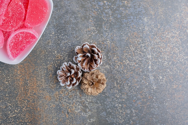 Une assiette blanche pleine de bonbons à la gelée de fruits rouges et de pommes de pin. Photo de haute qualité