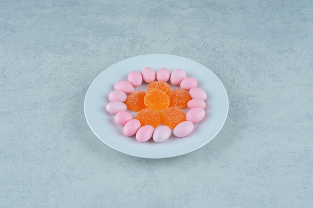 Une assiette blanche pleine de bonbons à la gelée d'orange douce et de bonbons roses