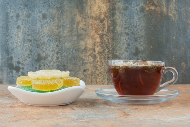 Photo gratuite une assiette blanche pleine de bonbons à la gelée de sucre et une tasse de tisane