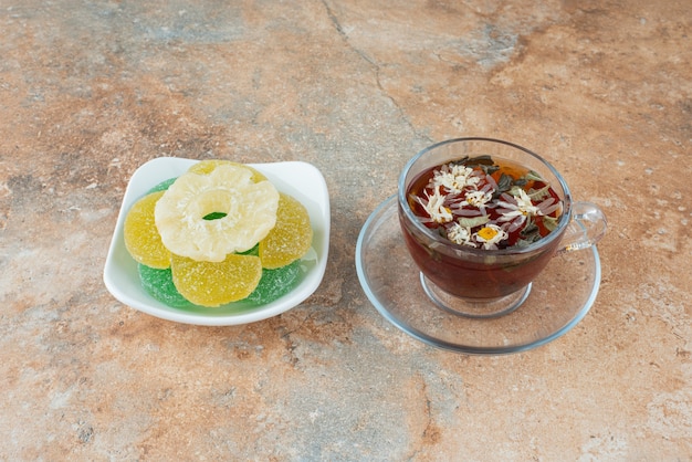 Une assiette blanche pleine de bonbons à la gelée de sucre et une tasse de tisane