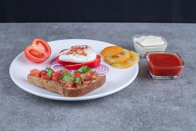 Une assiette blanche pleine de légumes tranchés et d'œufs durs