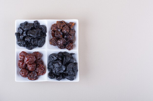 Assiette blanche pleine de prunes savoureuses séchées sur fond blanc. photo de haute qualité