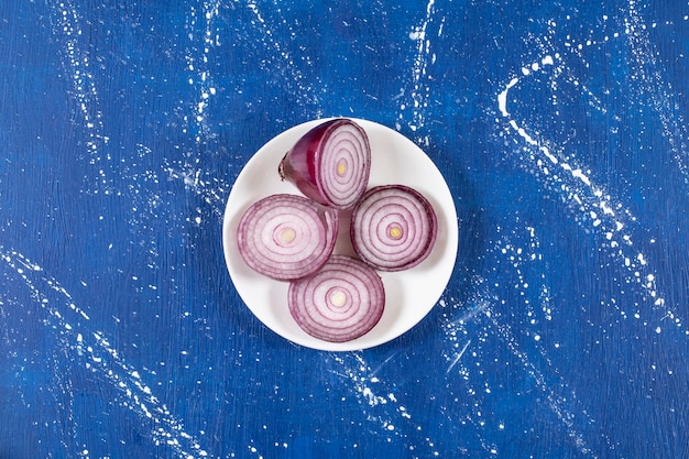 Assiette blanche avec rondelles d'oignon violet sur une surface en marbre