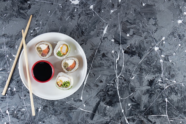 Assiette blanche de rouleaux de sushi au thon sur fond de marbre.