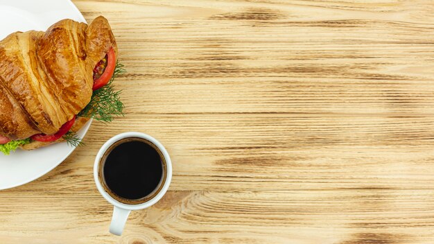 Assiette blanche avec un sandwich et une tasse de café