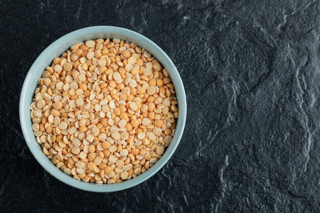 Une assiette bleue avec des lentilles non préparées dans un noir