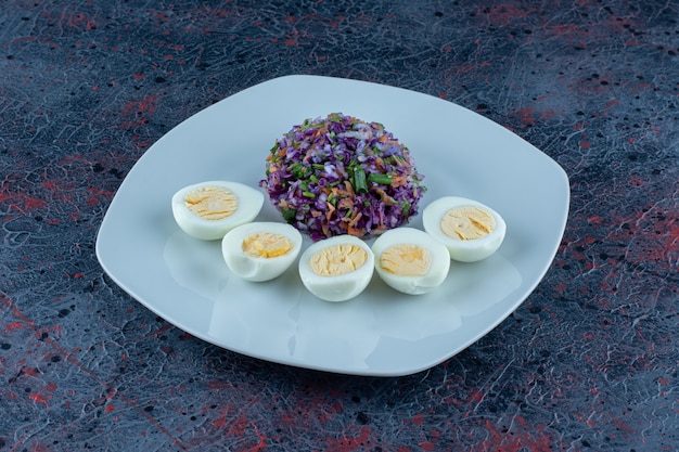 Une assiette bleue d'œufs durs avec des légumes.