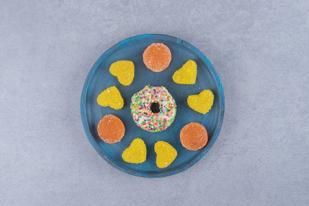 Assiette bleue avec un petit beignet et diverses marmelades sur une surface en marbre`