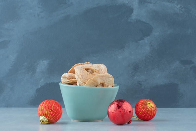 Une assiette bleue pleine de fruits secs et sains avec des boules rouges de Noël. Photo de haute qualité