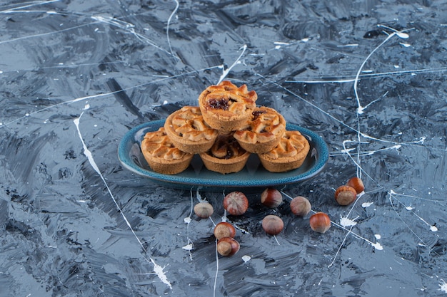 Photo gratuite une assiette bleue de tartelettes sucrées aux noix de macadamia sur une surface en marbre .