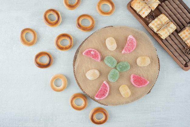 Une assiette en bois de bonbons à la gelée de sucre et de biscuits ronds sur fond blanc. Photo de haute qualité