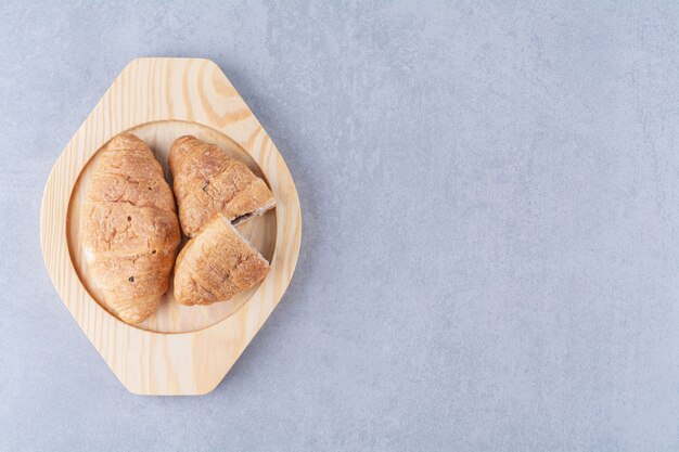 Une assiette en bois de croissants avec un délicieux chocolat.