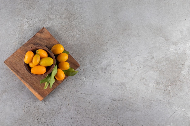 Assiette en bois de kumquats juteux frais sur la surface de la pierre