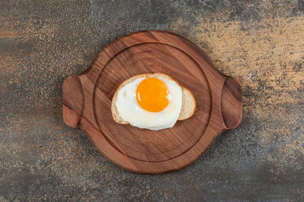 Une assiette en bois d'oeuf sur la tranche de pain blanc.