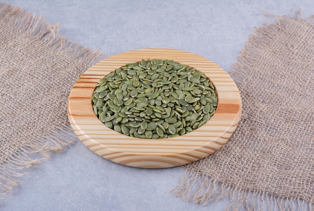 Assiette en bois de pepitas à côté de morceaux de tissu sur une surface en marbre