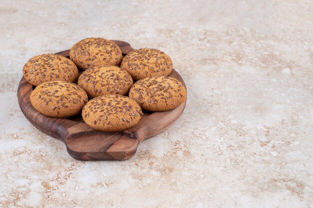 Assiette en bois pleine de biscuits à l'avoine sur une surface en marbre.