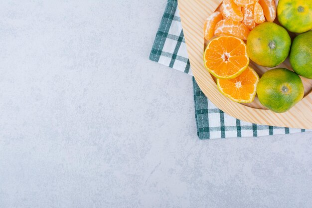 Photo gratuite assiette en bois pleine de mandarines aigres sur blanc