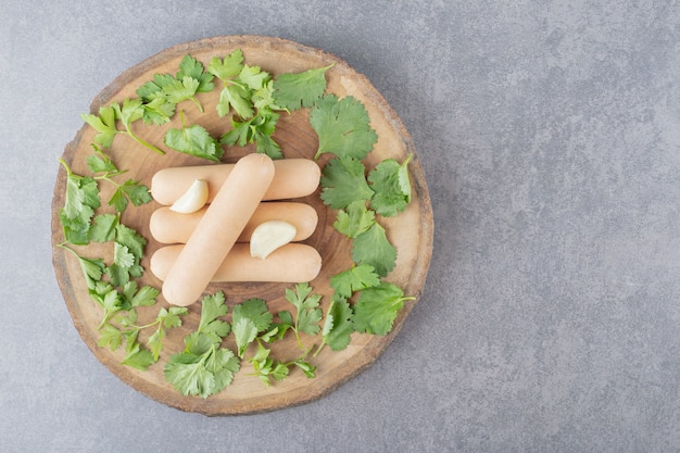 Photo gratuite une assiette en bois de saucisses bouillies avec du persil et de l'ail