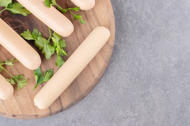 Une assiette en bois de saucisses bouillies avec du persil.